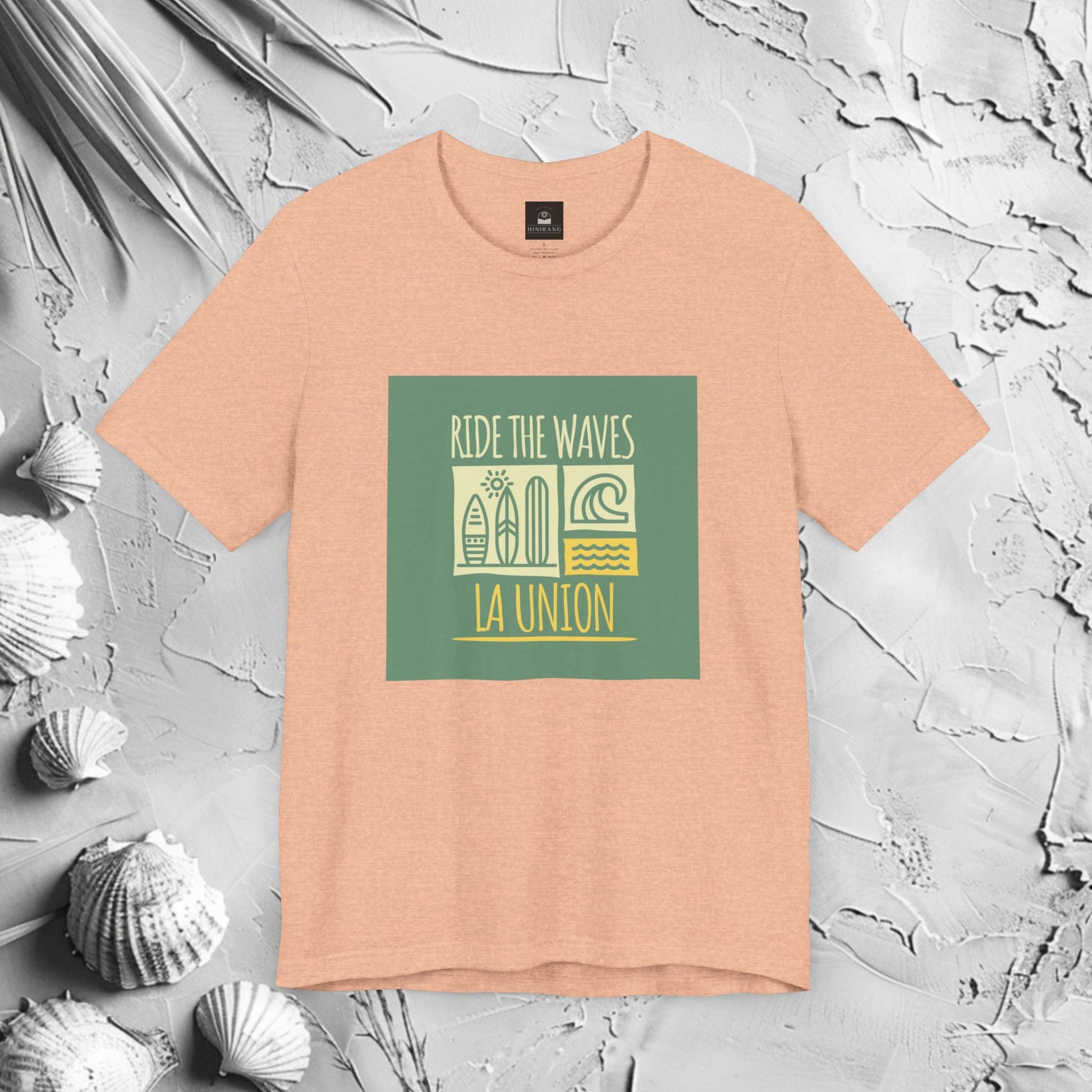 Ride The Waves La Union Graphic T-Shirt | Modern Filipino Clothing | HINIRANG. Embrace the surf culture with our Ride the Waves La Union T-Shirt, a must-have from a Filipino clothing brand that celebrates the thrill of La Union’s iconic waves. Designed for those who live for the sea, sun, and adventure.